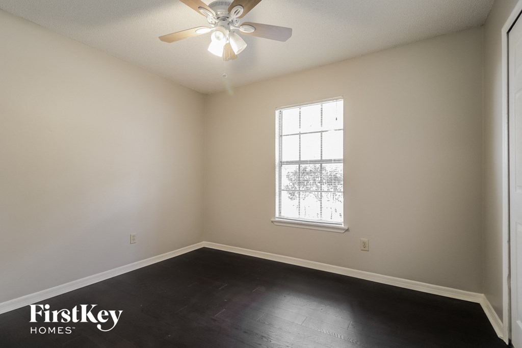 an empty room with a ceiling fan and a window