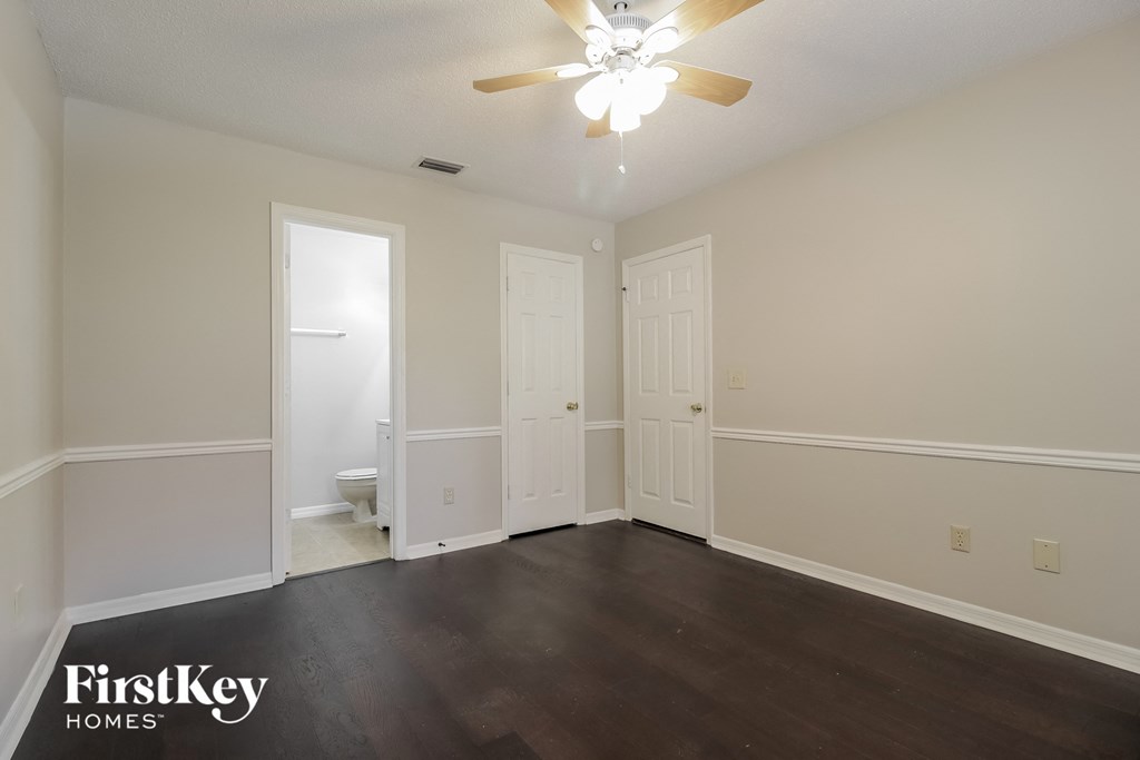 an empty living room with wood floors and a ceiling fan