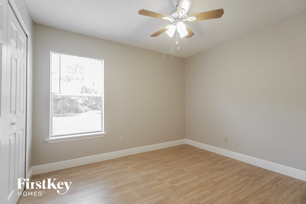 a bedroom with wood flooring and a ceiling fan