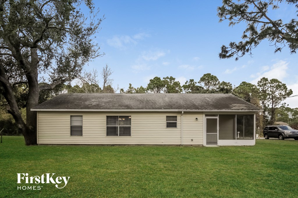 a small white house with a grassy yard and trees