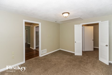 a bedroom with three doors and a carpeted floor