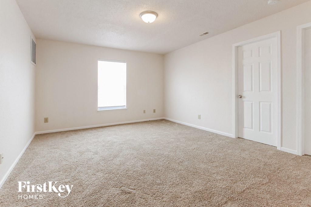 a spacious living room with carpet and a white door