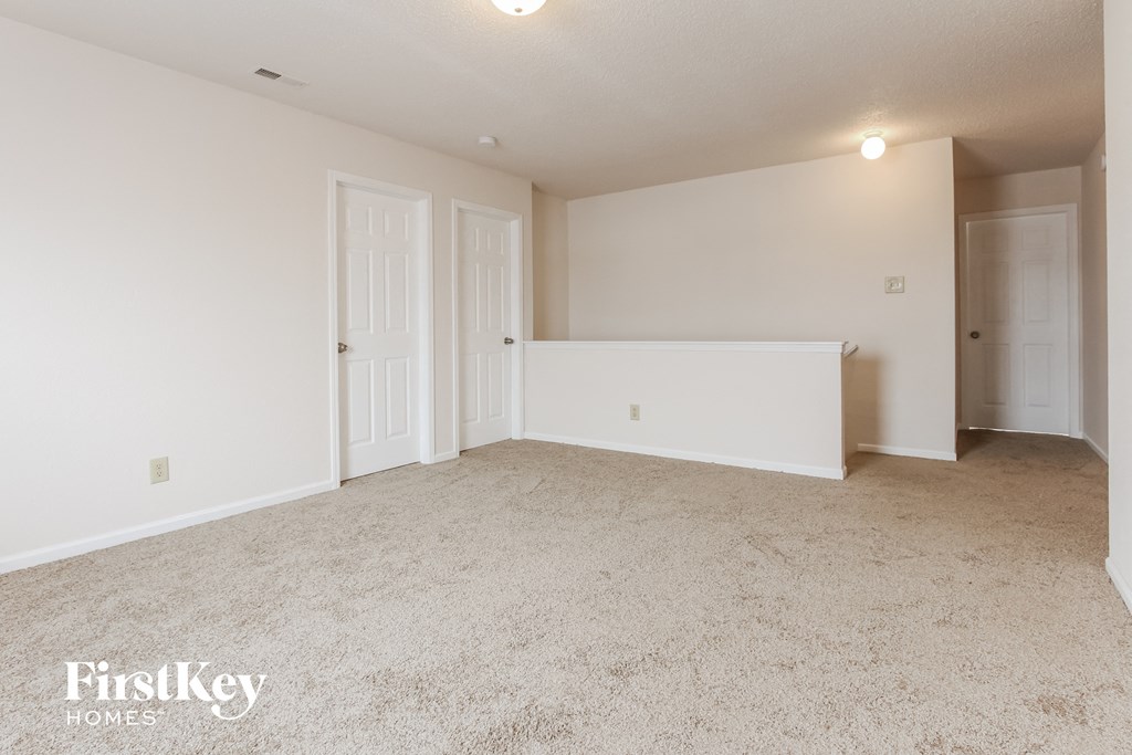 a spacious living room with white walls and a carpeted floor