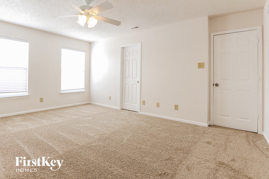 a empty living room with carpet and a ceiling fan