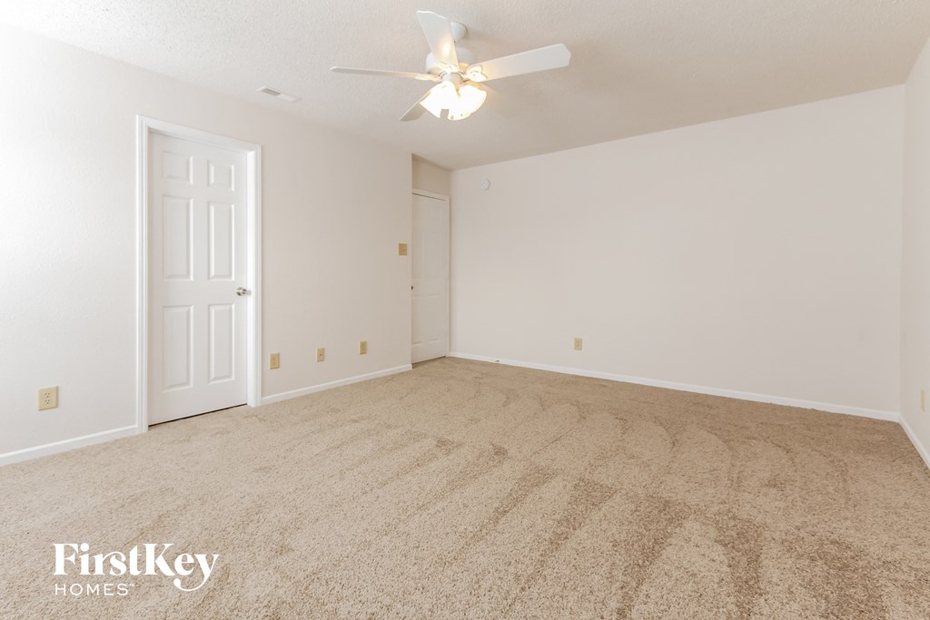 a spacious living room with carpet and a ceiling fan