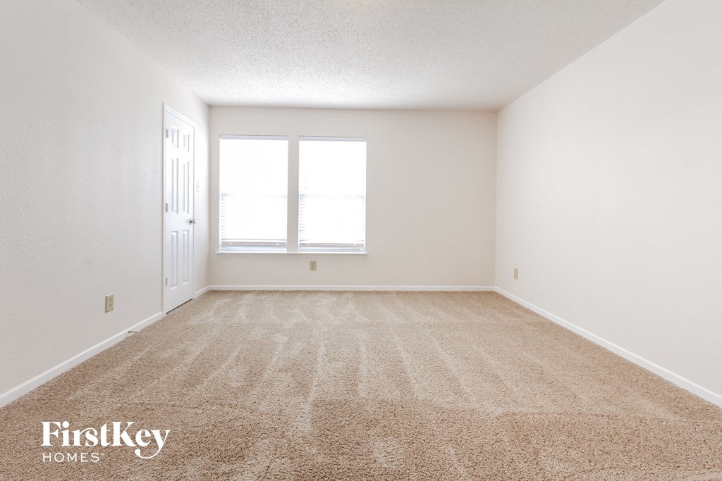 a spacious living room with carpet and a window