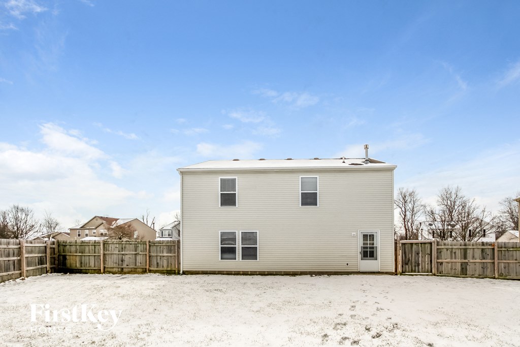 a small house with a sandy yard and a fence
