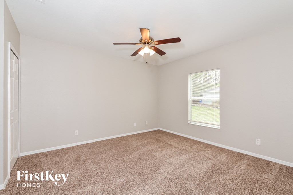 the living room of a home with carpet and a ceiling fan