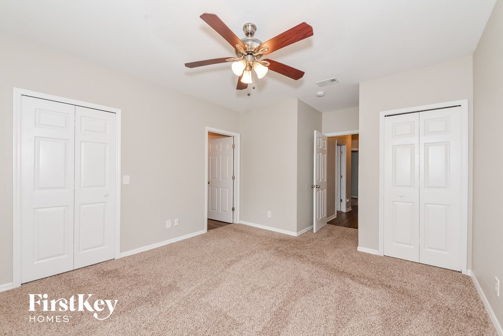 a spacious living room with carpet and a ceiling fan