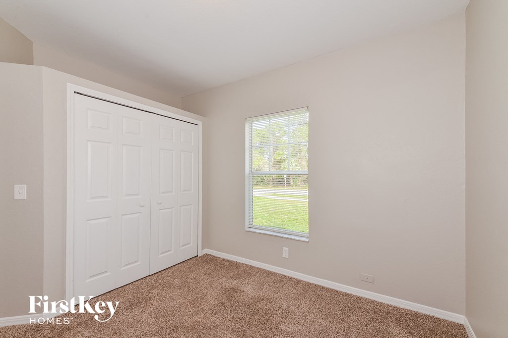 the bedroom of a home with a white door and carpet