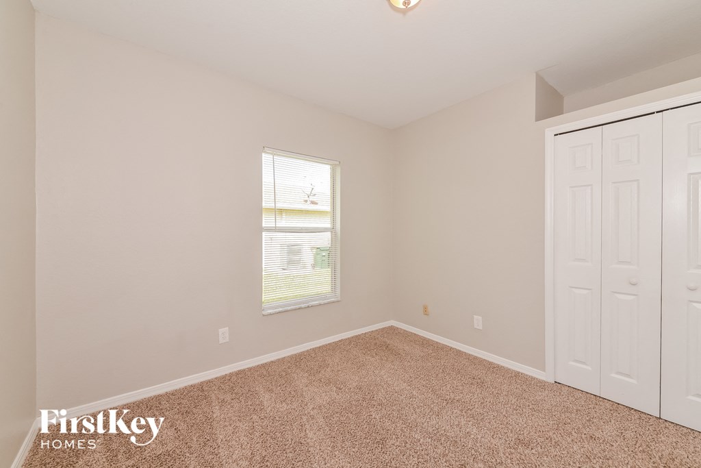 a bedroom with carpet and white doors and a window