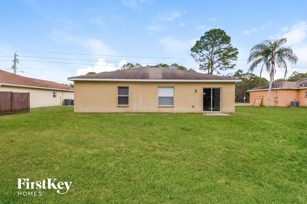 a beige house with a grass yard and palm trees