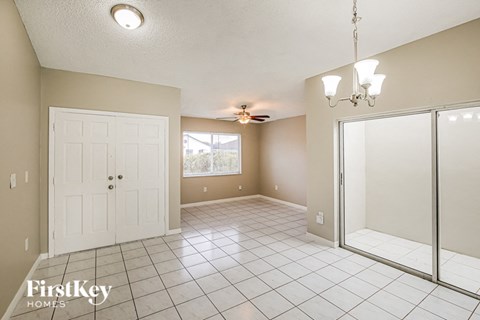 A spacious room with a white door, a ceiling fan, and a chandelier.