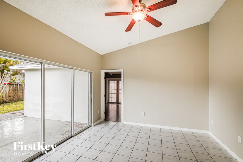 A room with a ceiling fan and sliding glass doors.