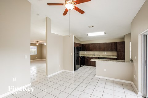 A spacious kitchen and living room with a ceiling fan.
