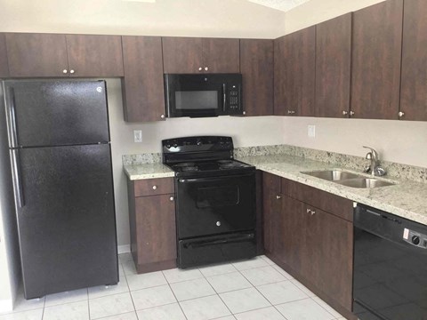 A black refrigerator stands next to a black oven in a kitchen.