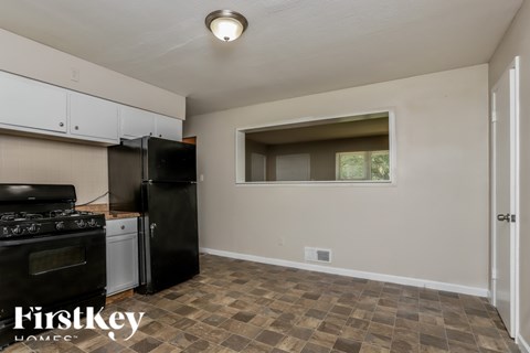 A kitchen with a black refrigerator and a tiled floor.