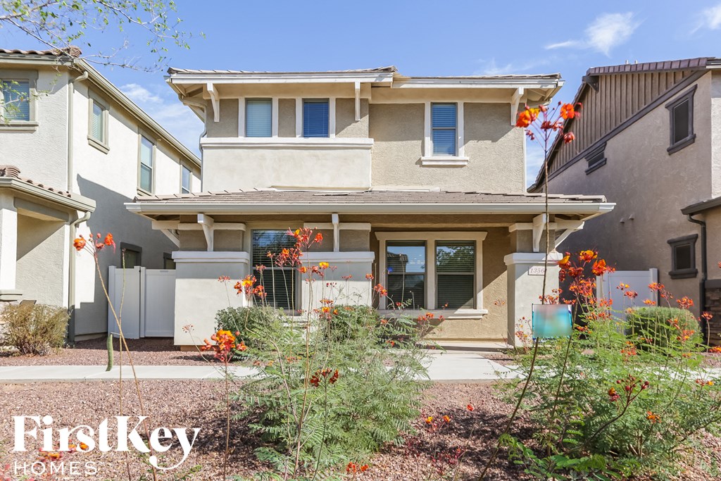 a beige house with orange flowers in the front yard