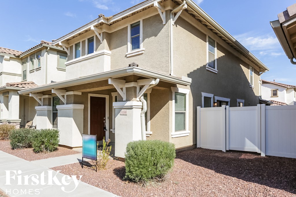 a tan house with a white fence and a white gate