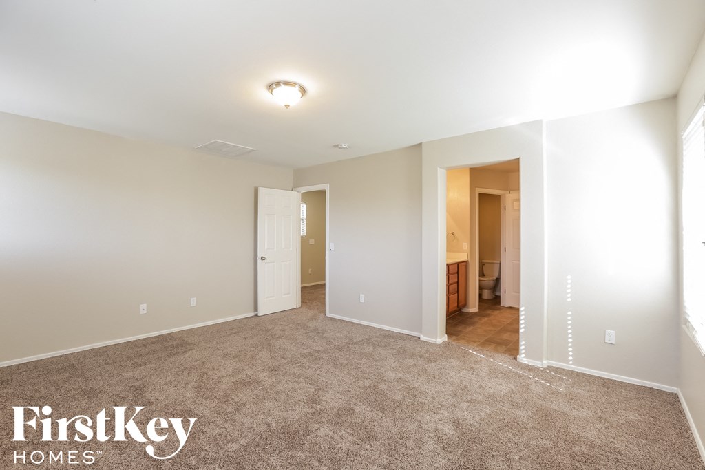 a bedroom with a carpeted floor and a door to a bathroom