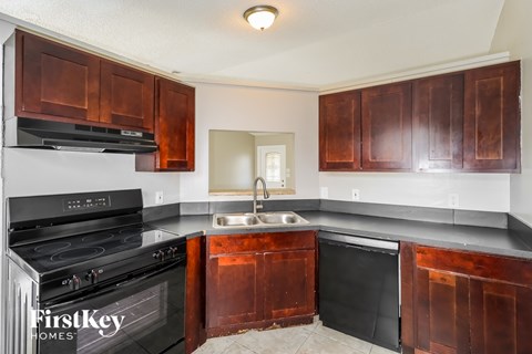 A kitchen with brown cabinets and black appliances.