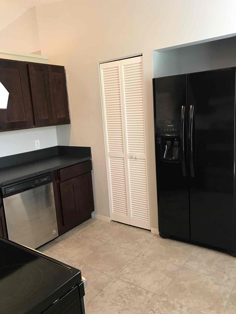 A black fridge and stove in a kitchen with white cabinets.
