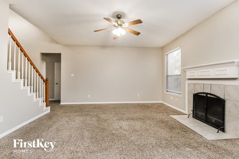 A spacious living room with a fireplace and a ceiling fan.