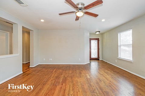 A spacious room with a ceiling fan and wooden flooring.