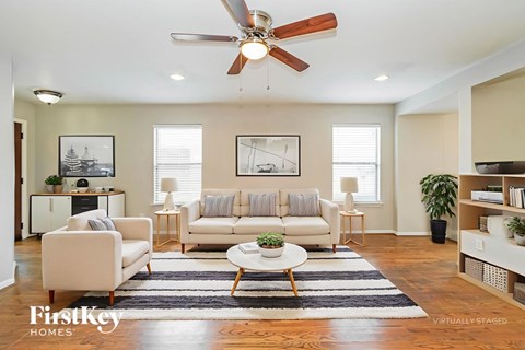 A living room with a white couch, a coffee table, and a ceiling fan.