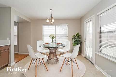 A dining room with a glass table and white chairs.