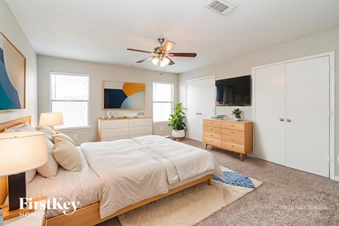 A bedroom with a bed, dresser, and ceiling fan.