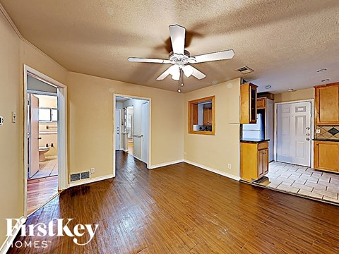 A spacious room with wooden floors and a ceiling fan.