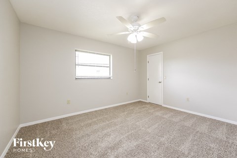 a spacious living room with carpet and a ceiling fan