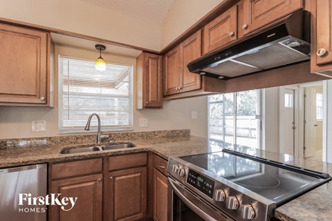 A kitchen with wooden cabinets and a stainless steel stove top.