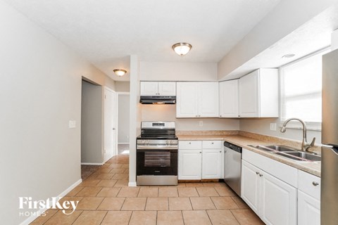 A kitchen with white cabinets and a tile floor.