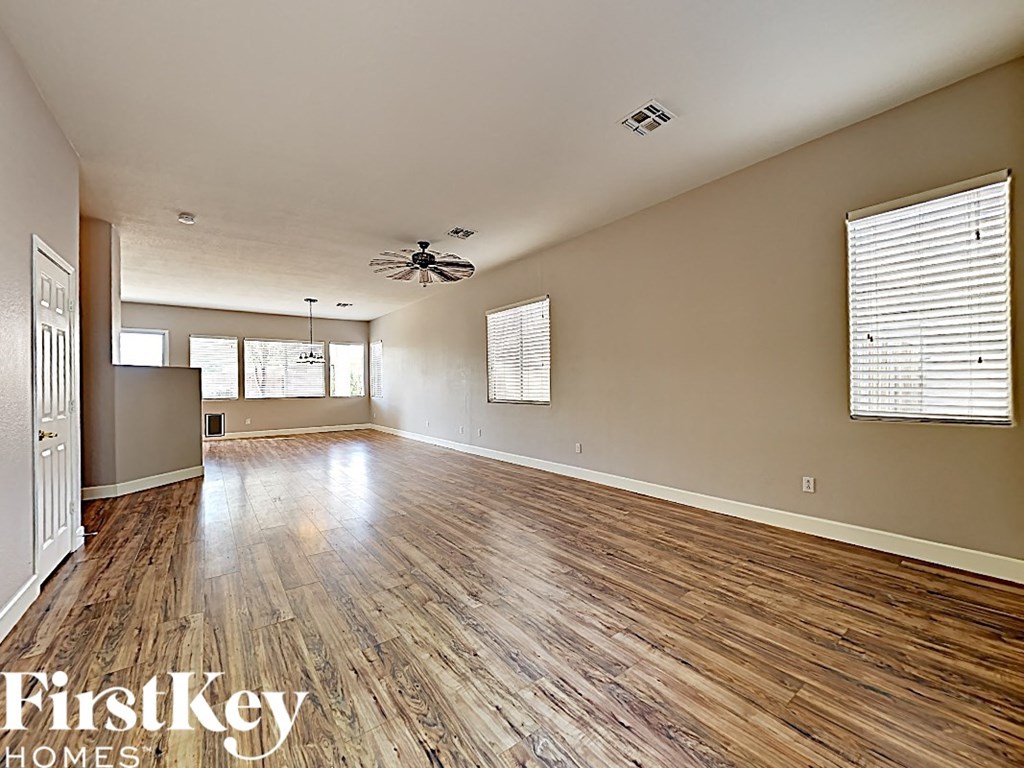 an empty living room with wood flooring and a ceiling fan