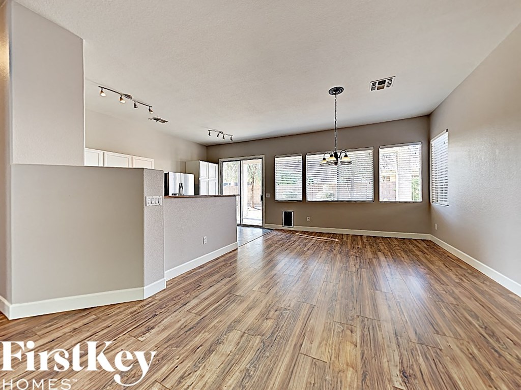 an empty living room with wood flooring and a kitchen