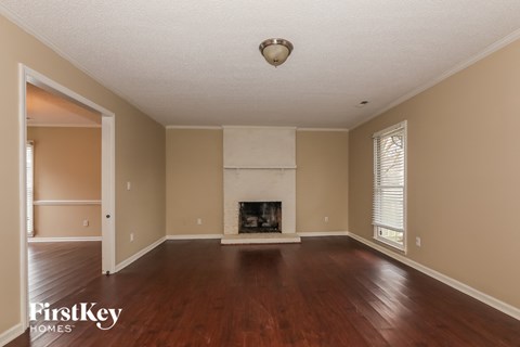 an empty living room with a fireplace and wooden floors