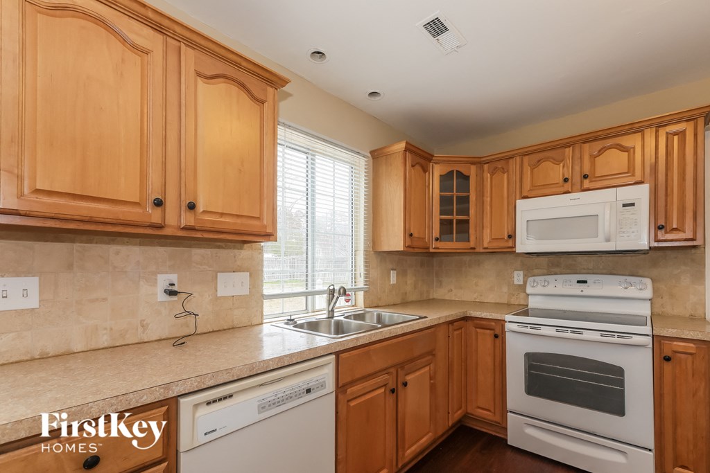 a kitchen with wooden cabinets and white appliances and a sink