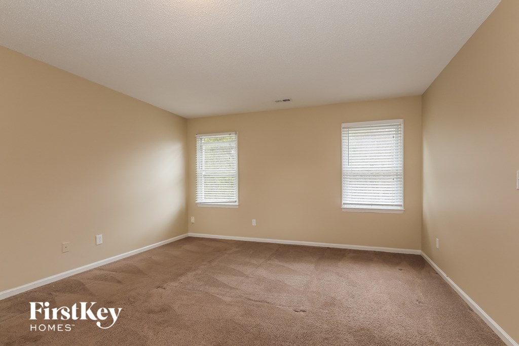 an empty room with carpet and two windows