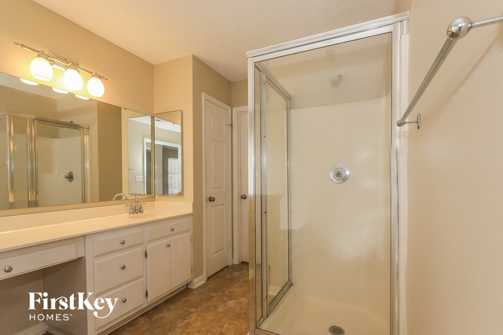 the master bathroom has a large vanity and a shower
