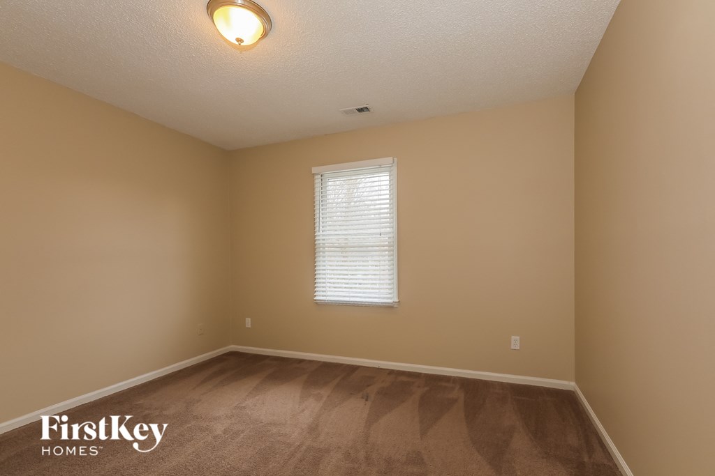 the upstairs bedroom with hardwood flooring and a window