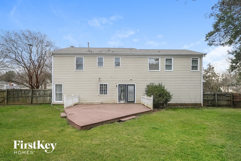 a yellow house with a wooden deck in a backyard