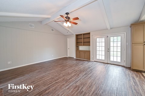 A spacious room with wooden flooring and a ceiling fan.