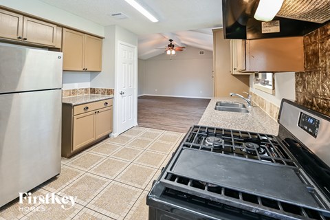 A kitchen with a stove top oven and a refrigerator.