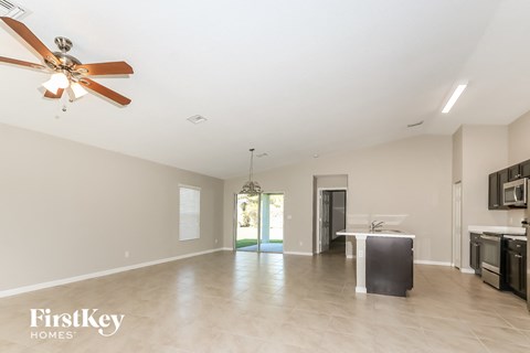 A spacious room with a ceiling fan and a kitchen area with appliances.