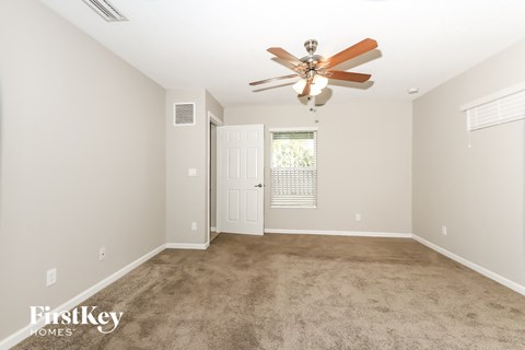 A spacious room with a ceiling fan and carpeted floor.