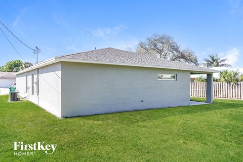A small white building with a FirstKey HOMES sign on the lawn.