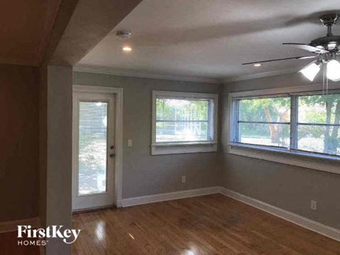 an empty living room with a ceiling fan and three windows