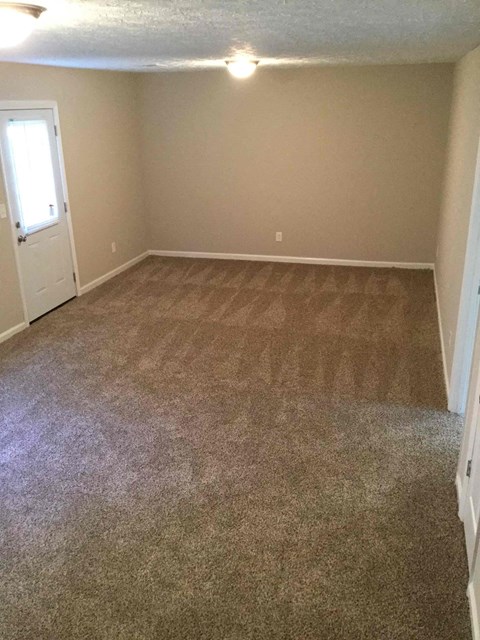 A room with a carpeted floor and a door.
